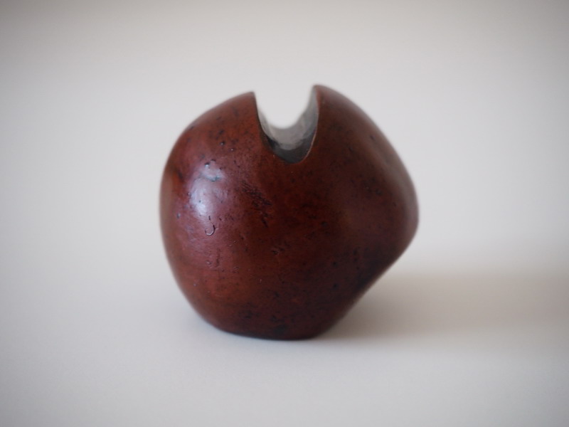 Scultura chiusa in argilla bruna a forma sferica con apertura superiore che mostra un interno scuro – Op. 56/25.