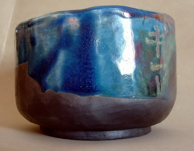 Tazza da tè in ceramica raku dai colori intensi, con sfumature che richiamano il mare e la terra, con finitura lucida e forma unica ispirata alla tradizione giapponese.
