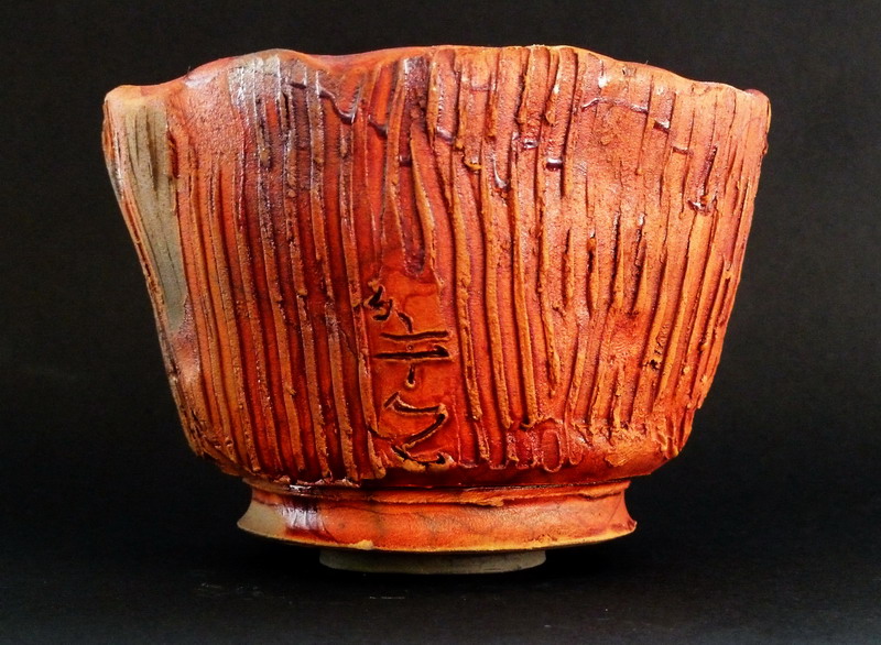 Tazza da tè in ceramica raku con superficie irregolare e segni di cottura unici, ispirata alla tradizione giapponese.