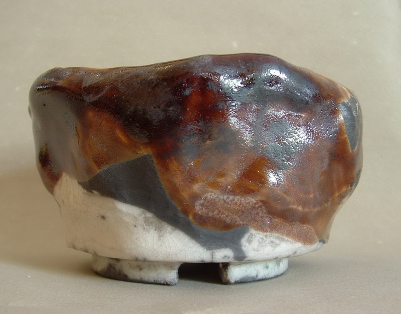 Tazza da tè giapponese in ceramica raku, dalla superficie unica, con texture e sfumature calde, simbolo di autenticità e imperfezione.