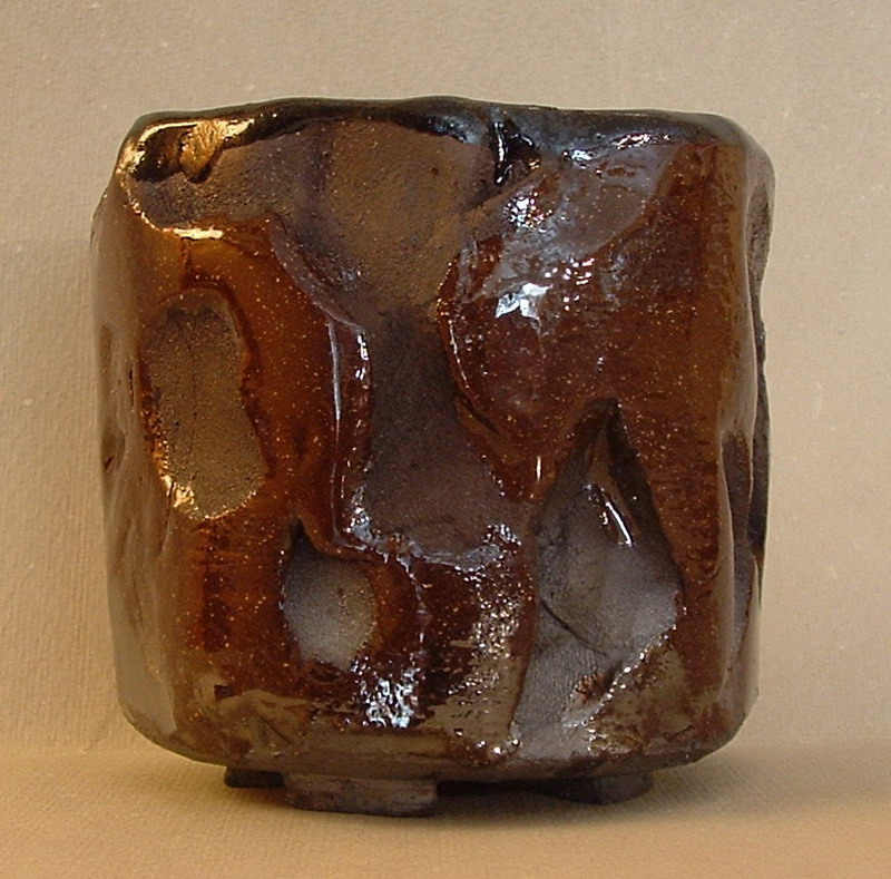 Tazza da tè in ceramica raku con finitura lucida e forme scolpite, ispirata alla tradizione giapponese del raku.